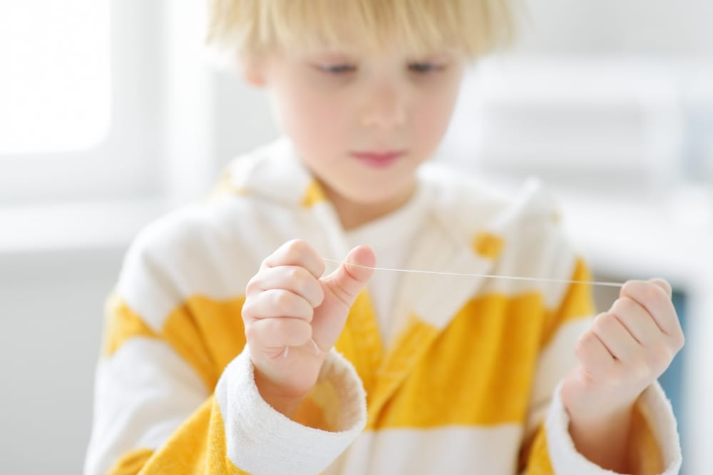 Un jeune garçon apprend à passer la soie dentaire